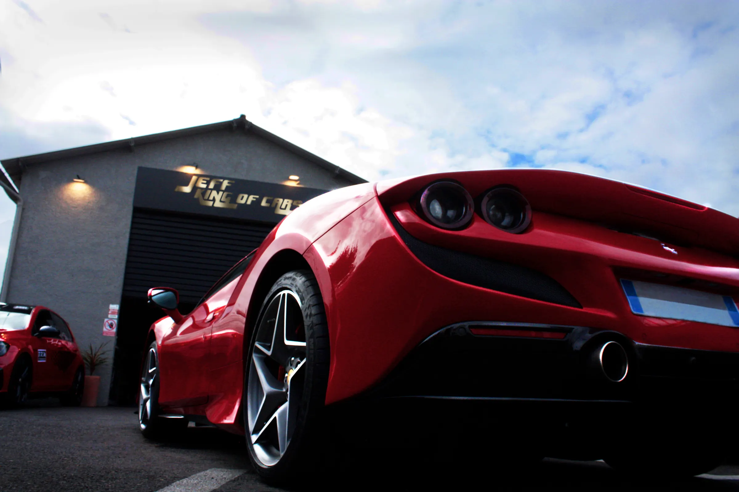 Ferrari F8 Tributo rouge devant la façade de l'atelier Jeff King of Cars